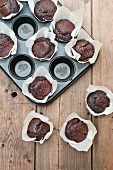 Chocolate muffins in parchment paper, some in a muffin tin