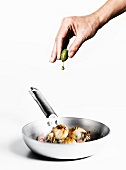 Hand presst Olivenöl aus Olive auf Sepia mit Knoblauch