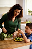 Mutter und Sohn zerkleinern Brokkoli in der Küche