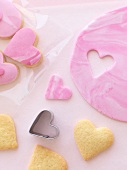 Pink heart-shaped biscuits being cut out