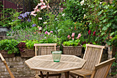 Wooden table and chairs surrounded by plants on terrace