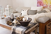 Decorative items on rustic coffee table in front of striped sofa with cushions and fur blanket