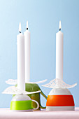 Upturned cups used as candle holders with doilies as drip protectors