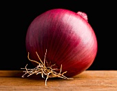 Eine rote Zwiebel auf Holzplatte