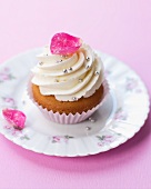 An elegant cupcake decorated with a candied rose petals and silver balls
