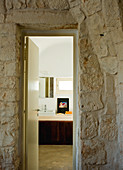 Anteroom with stone wall and view of modern washstand through open bathroom door