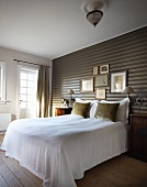 Elegantes Schlafzimmer - Bett mit weißem Überwurf vor gestreifter Tapete an Wand