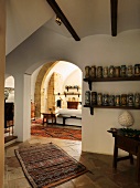 Sammlung von Keramikvasen auf Regalen neben Rundbogen und Blick ins mediterrane Wohnzimmer