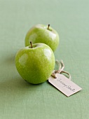 Two Granny Smith apples with a label