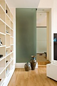 Corner of modern living room - Chinese vases against glass wall next to doorway and modern, white fitted shelving