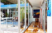 Glazed hallway in modern house with view of table and chairs on terrace