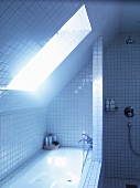Unter Dachschräge eingebautes Bad mit weissen Fliesen an Wand, Badewanne und Boden