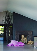 Pink cushions on floor in front of open fireplace and black-painted wall