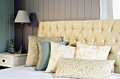 Upholstered headboard and pillows on front of a wooden wall