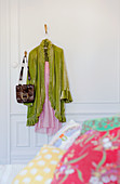 Light green dressing gown over nightdress and bag hanging from wall hooks in bedroom with traditional ambiance