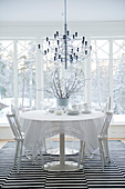 Designer Hängeleuchte über Esstisch und Stühle in Weiß auf Teppich mit schwarz-weissen Streifen