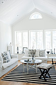 Heller Wohnraum im Dachgeschoss mit weisser Polstergarnitur und orientalischem Beistelltisch auf schwarz-weißem Teppich
