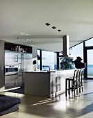 Designerküche mit freistehendem Küchenblock vor verglaster Fensterfront