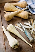 Parsnips, some peeled, on a wooden surface