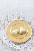Two white chocolate hearts on a golden plate
