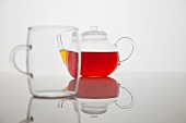 Tee in Glaskanne hinter leerem Glas