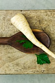 A parsnip and parsley on a wooden spoon
