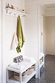 Badezimmerecke mit grünem Handtuch an Wandhakenleiste über halbhohem Regal neben Ganzkörperspiegel
