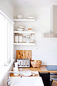 Weisses Spülbecken, Arbeitsplatte aus Holz und weiße Wandregale in einer Küche