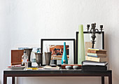 Zinnbecher, Vasen, Bücherstapel und Allerlei auf modernem Wandtisch