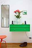 Bright green floating cabinet with drawers and tall mirror on wall of foyer