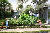 Kinder gießen die Pflanzen im Garten