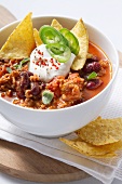 Chili con carne with sour cream and tortilla chips