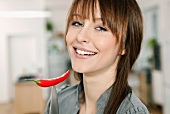 A woman holding a chilli pepper on a knife