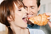 A woman biting into a croissant with jam