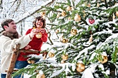 Young couple decorating Christmas tree in garden