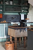 Chopping block side table with integrated knife block in front of simple kitchen counter with plate rack above sink