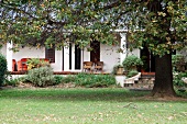 Autumnal garden in front of traditional house with columns on veranda