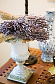 Getrocknete Blüten und Zweige auf griechisch antiker Vase und Beistelltisch mit Lochholz Platte