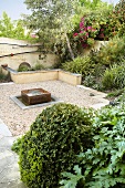 Relaxation area in lushly planted gravel garden with modern fountain