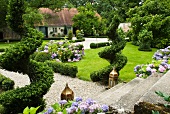 Sommergarten auf zwei Ebenen mit blühenden Hortensien und Buchs-Spiralen