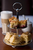 A cake stand and a latte macchiato in the background