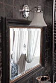 Vintage Spiegel mit Wandleuchte an gefliester Wand in mediterranem Bad