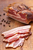 A piece of Tyrolean bacon and slices with peppercorns
