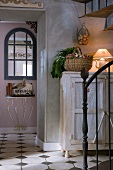 Foyer of old country house in shabby chic style with artistic metal staircase and original antique console table in background