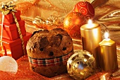 An arrangement of panettone, candles, Christmas baubles and gifts
