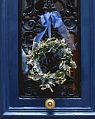 Winterlicher Türkranz an blauer Haustür hängend