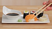 Nigiri-Sushi mit Stäbchen entnehmen