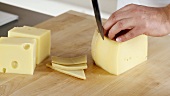 Rind being cut off a piece of cheese being