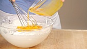 Beaten egg yolk being folded into beaten egg white