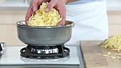 Grated cheese being added to a fondue pot